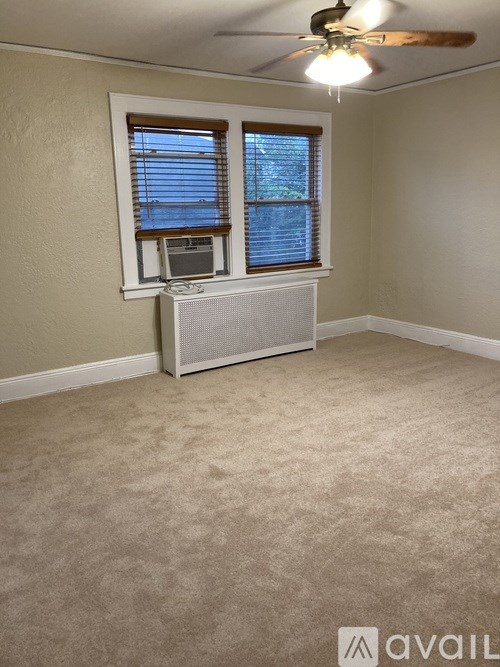 A room with a ceiling fan and a window with blinds.