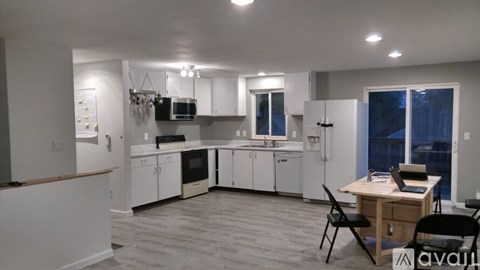 A kitchen with white cabinets and a wooden table.