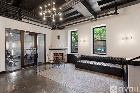 A living room with a black couch and a fireplace.