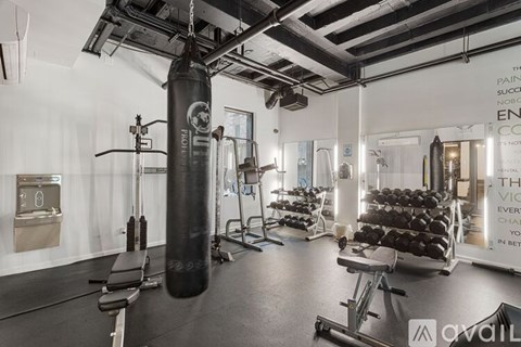 A gym with a punching bag, weights, and exercise equipment.