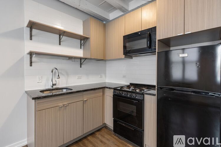 A kitchen with a black stove and oven, wooden cabinets, and a black microwave.
