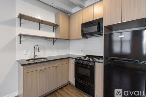A kitchen with a black stove and oven, wooden cabinets, and a black microwave.