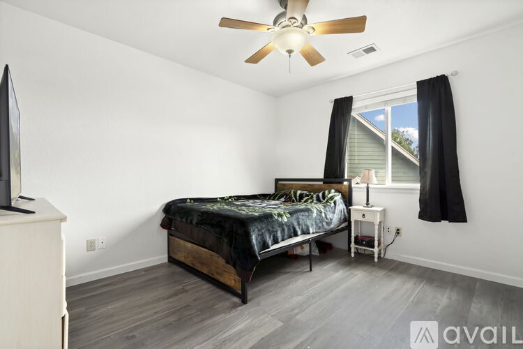 A bedroom with a bed, a television, and a window with black curtains.