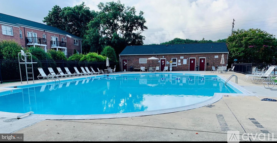A large outdoor swimming pool surrounded by lounge chairs and a small building.