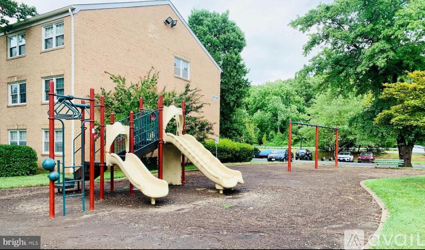 A playground with a yellow slide and red poles.