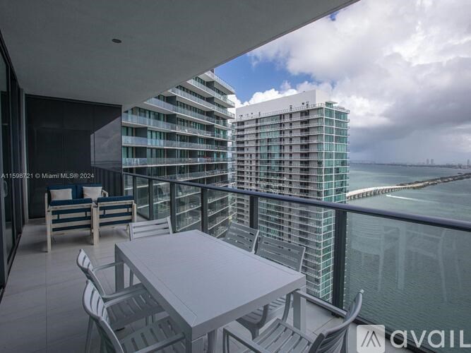 A balcony with a table and chairs overlooks a body of water.