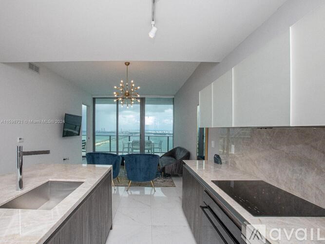 A modern kitchen with a marble countertop and a large window overlooking the city.