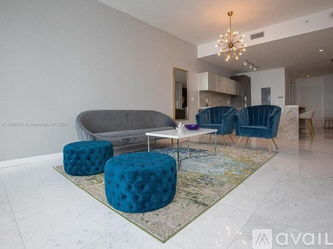 A living room with a grey sofa, blue ottoman, and a chandelier.