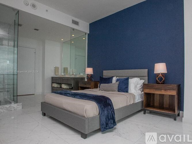 A bedroom with a bed, nightstand, and a wall-mounted lamp.