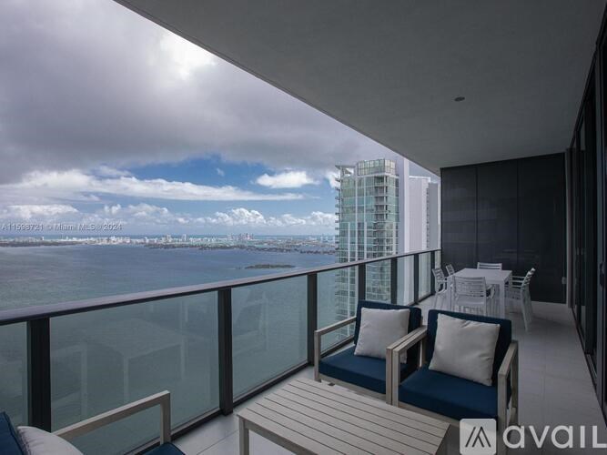 A balcony with two chairs and a table overlooking a cityscape.