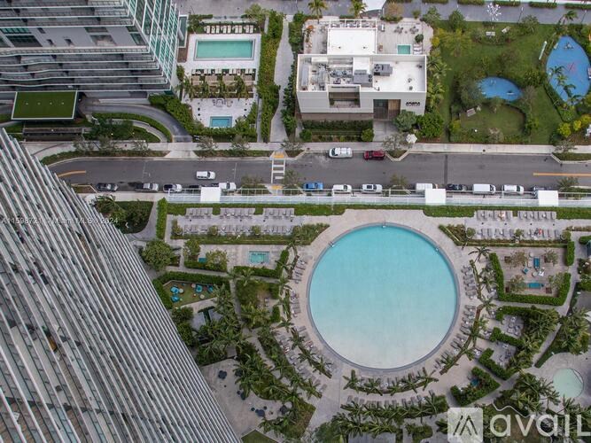 A bird's eye view of a round pool surrounded by greenery and buildings.