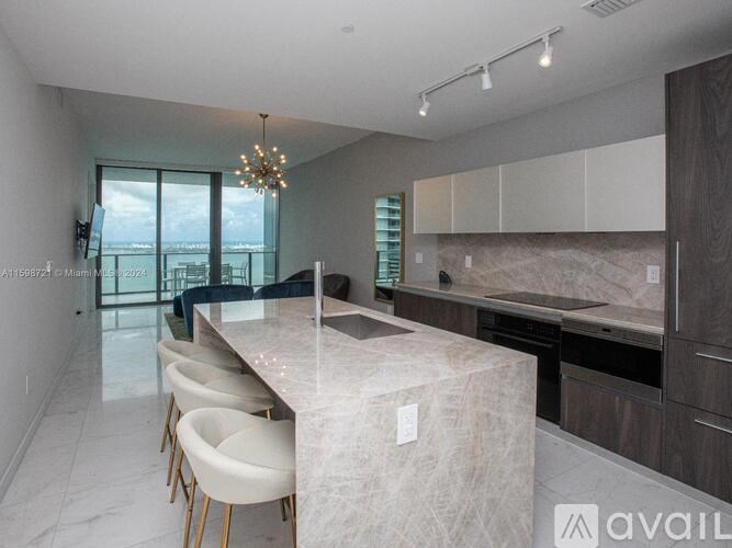 A modern kitchen with a marble island and chairs.