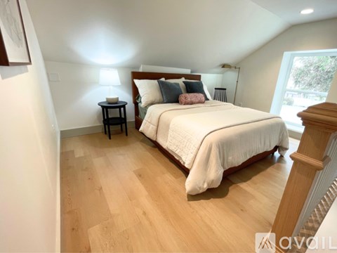 A bedroom with a large bed and a wooden floor.