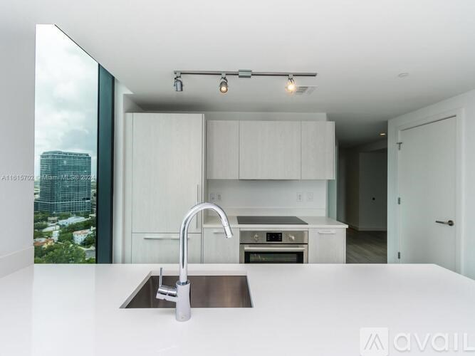 A modern kitchen with a stainless steel sink and white cabinets.