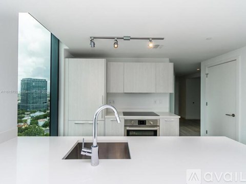 A modern kitchen with a stainless steel sink and white cabinets.