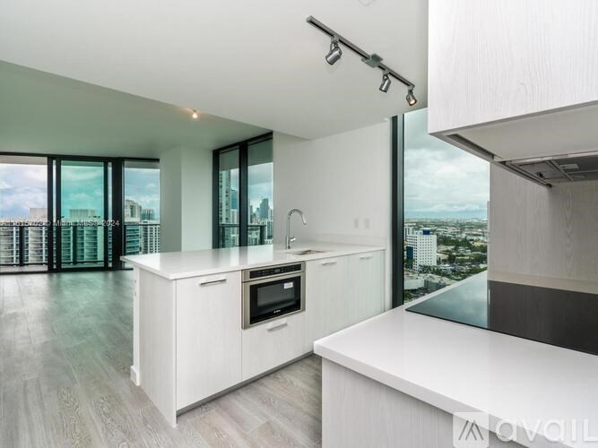 A modern kitchen with white cabinets and a view of the city.
