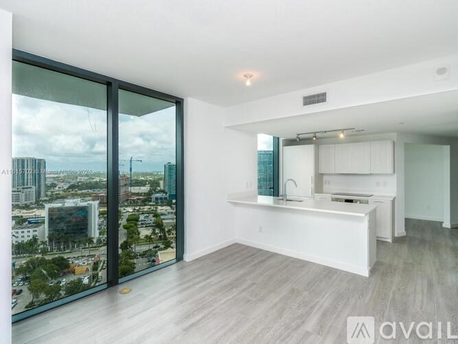 A modern kitchen with a view of the cityscape outside the large window.