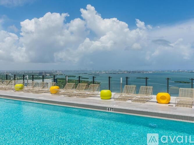 A pool with yellow chairs and a view of the city in the distance.