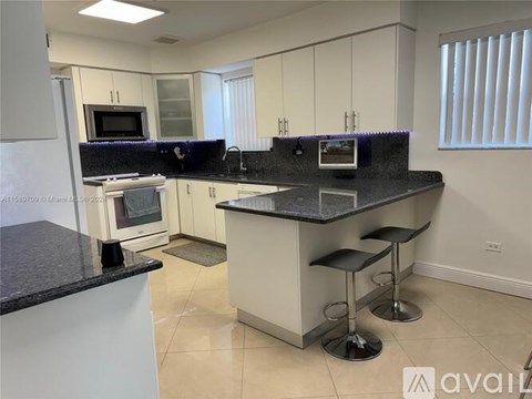 A kitchen with white cabinets and a black countertop.