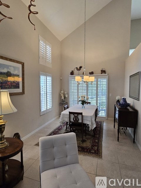 A dining room with a table set for two and a painting on the wall.