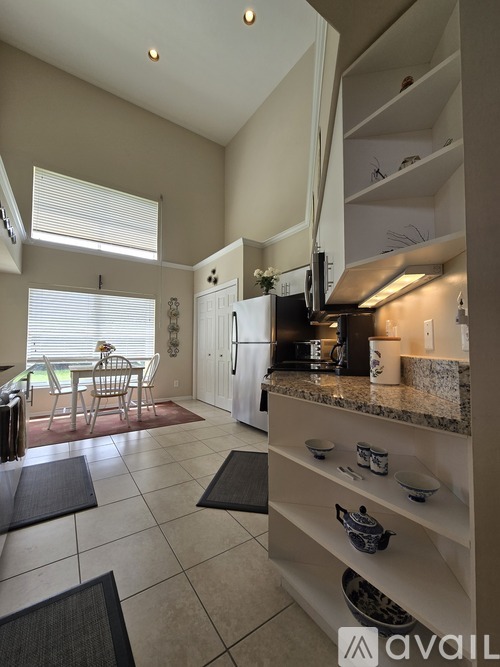 A kitchen with a refrigerator, sink, and a dining table with chairs.