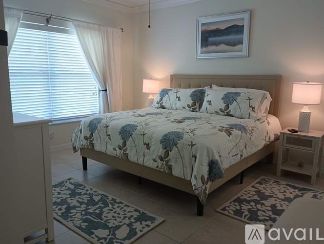 A bedroom with a large bed and a painting on the wall.