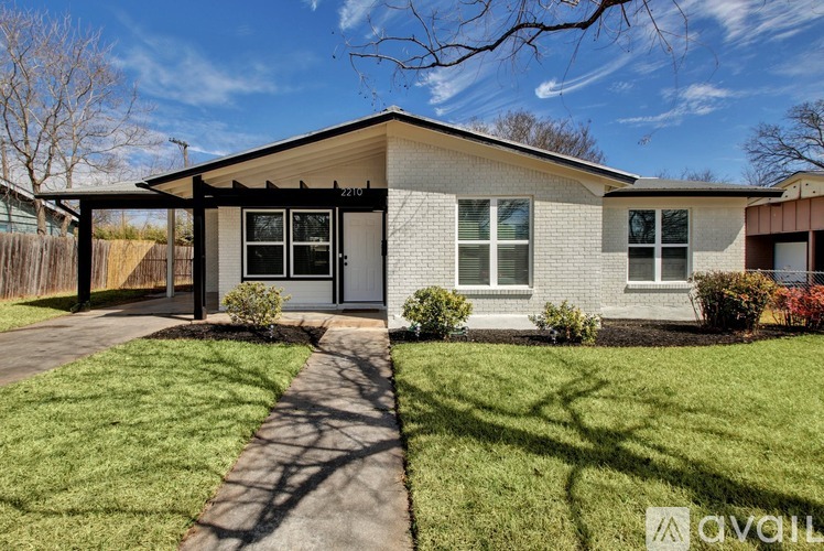 A house with a white facade and a brown roof is for sale.