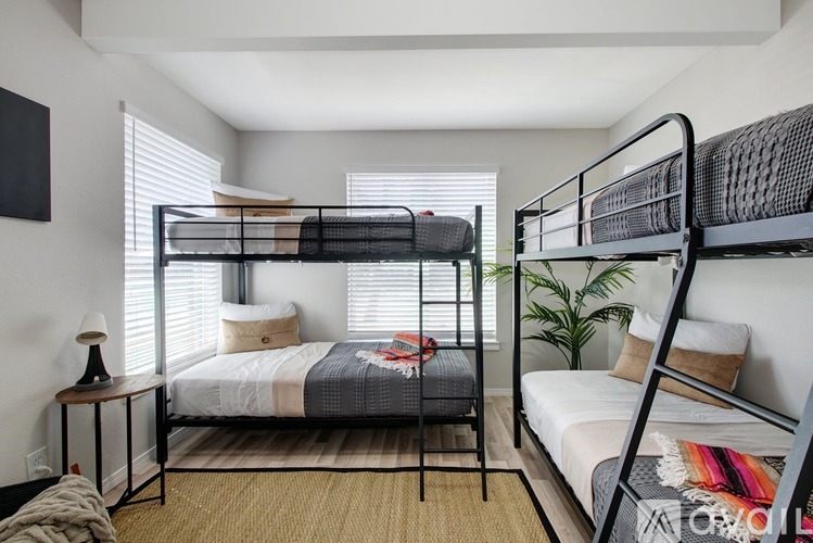 A bedroom with two bunk beds and a small table with a lamp.