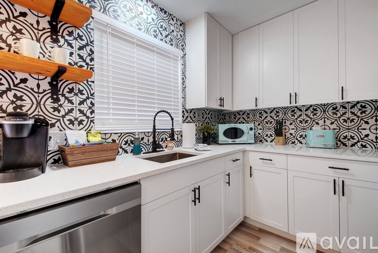 A kitchen with white cabinets and a black and white tiled backsplash.