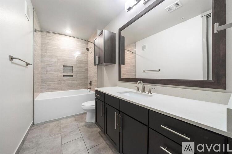 A bathroom with a tub, toilet, sink, and mirror.