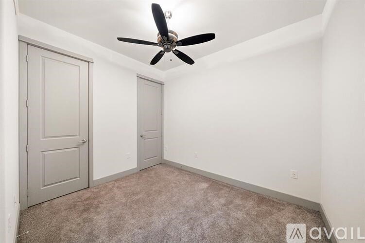 A room with a ceiling fan and two doors.