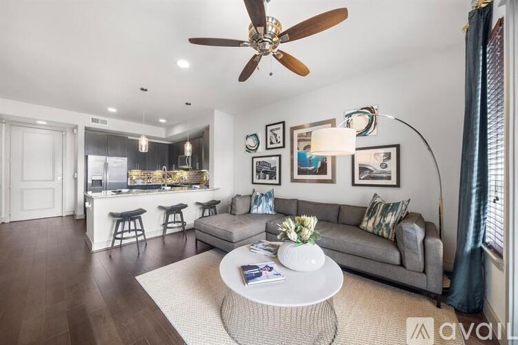 A living room with a grey couch, a white coffee table, and a ceiling fan.