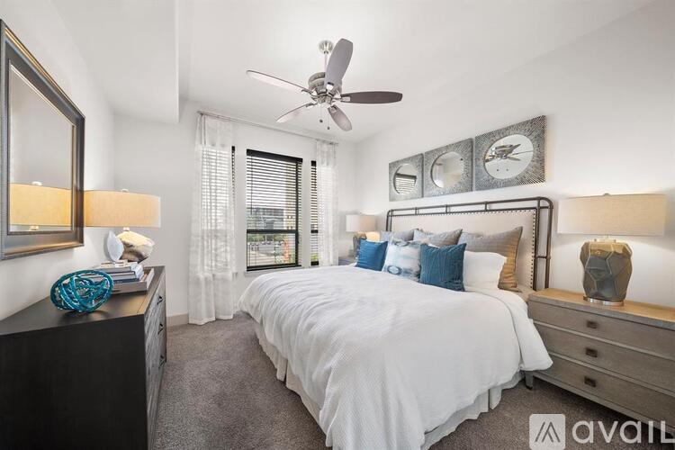 A bedroom with a large bed, a ceiling fan, and a window with blinds.