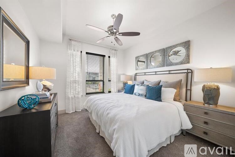 A bedroom with a large bed, a ceiling fan, and a window with blinds.