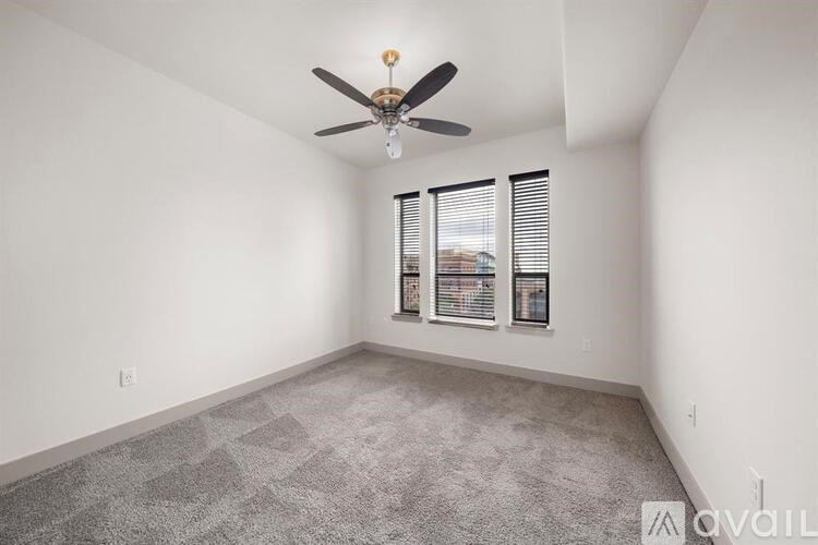 A room with a ceiling fan and a window with blinds.