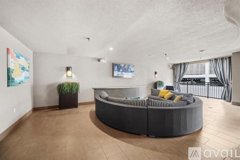 A living room with a grey sofa and a flat screen TV mounted on the wall.
