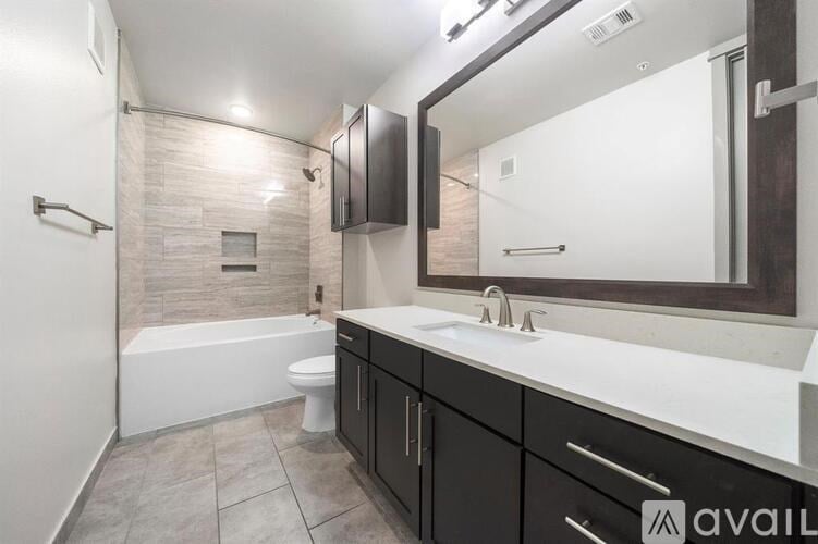A bathroom with a tub, toilet, sink, and mirror.