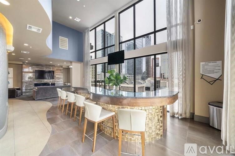 A modern bar area with a curved wooden counter and white chairs.