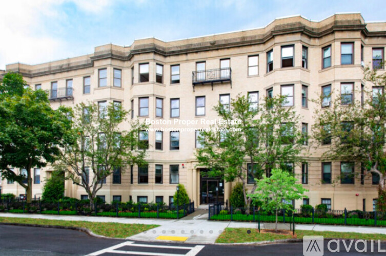 A large, beige building with a black fence in front.