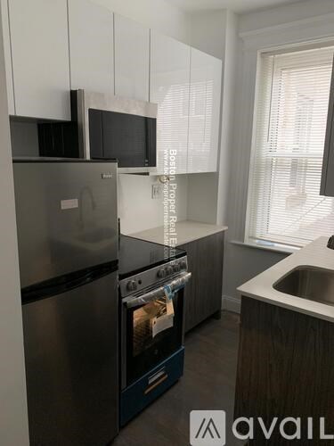 A kitchen with a stainless steel refrigerator and oven, and a sink with a window above it.