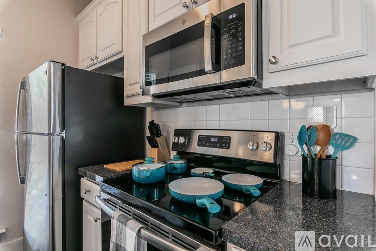 A kitchen with a black fridge, a black microwave, and a black stove top.