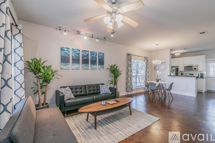 A living room with a black couch, a coffee table, and a ceiling fan.