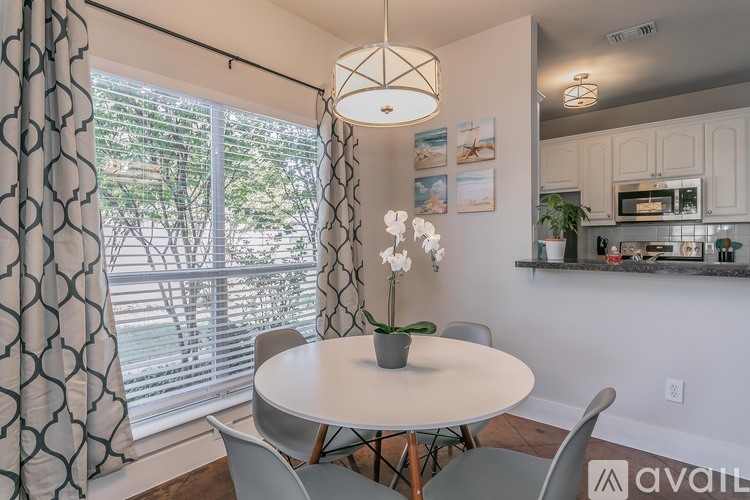 A dining room with a table, chairs, and a plant.
