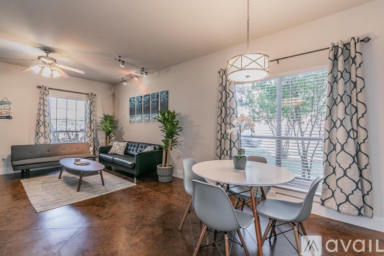 A living room with a grey couch, a white table, and a ceiling fan.