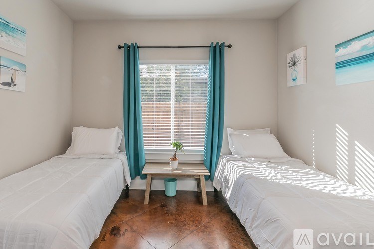 A bedroom with two beds and a window with a plant on the table.
