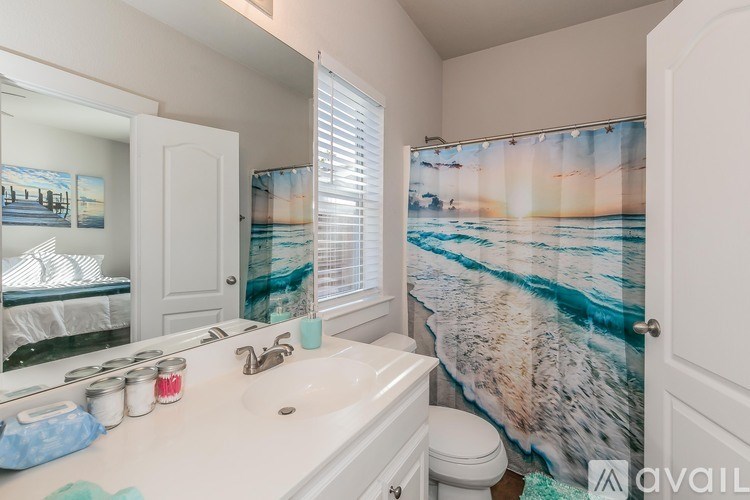 A bathroom with a white sink and a shower curtain with a beach scene on it.