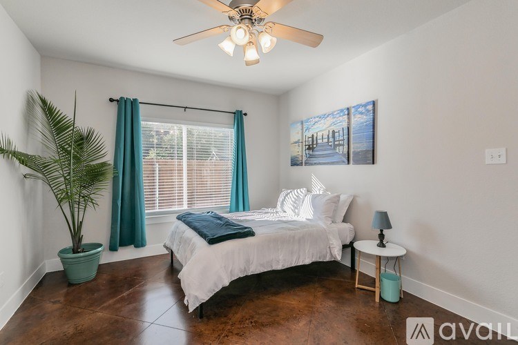 A bedroom with a bed, a ceiling fan, and a potted plant.