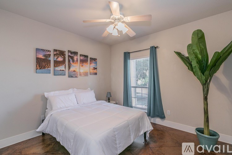 A bedroom with a white bed and a ceiling fan.