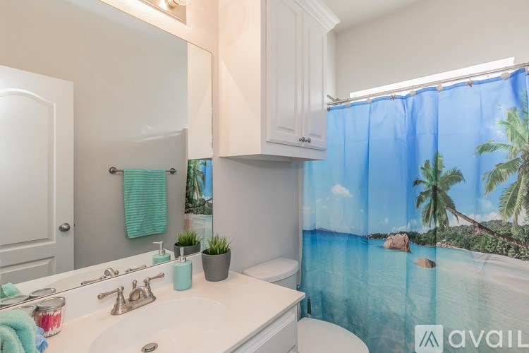 A bathroom with a tropical beach scene on the shower curtain.