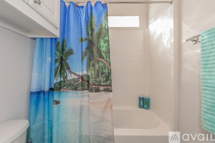 A bathroom with a tropical beach scene on the shower curtain.